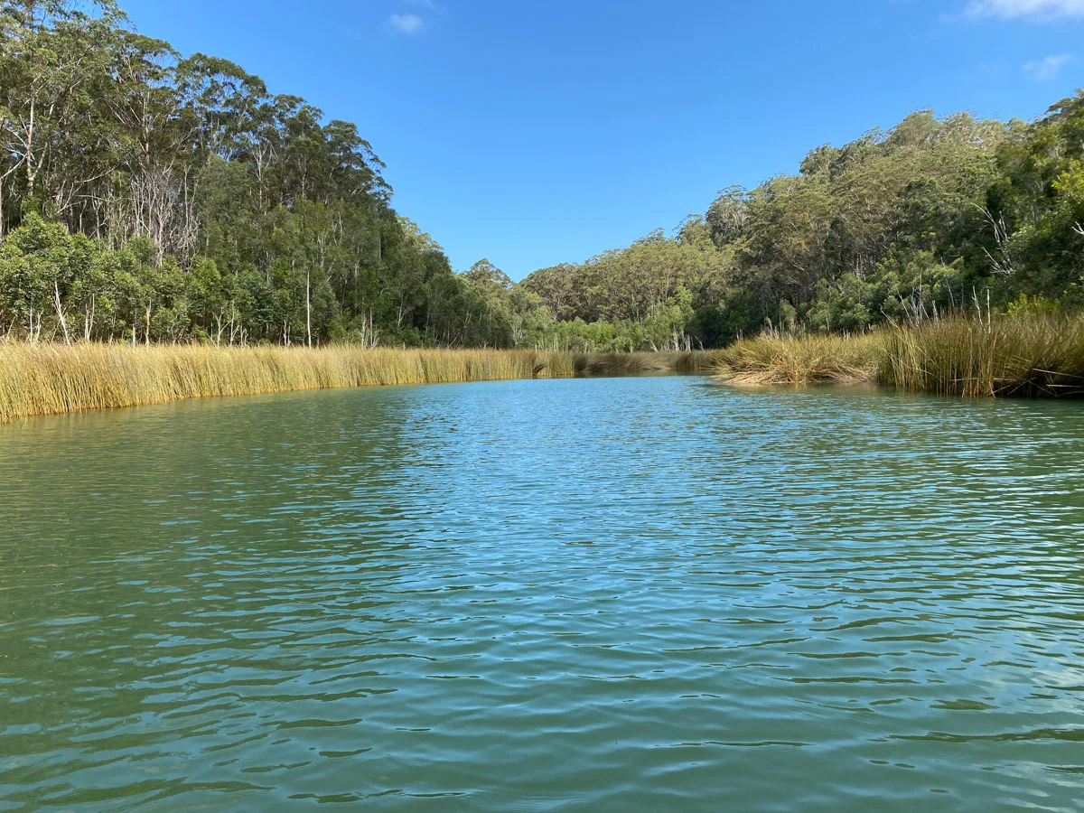 Lago de K'gari con aguas claras y nivel reducido, conectado a un sistema subterráneo más profundo