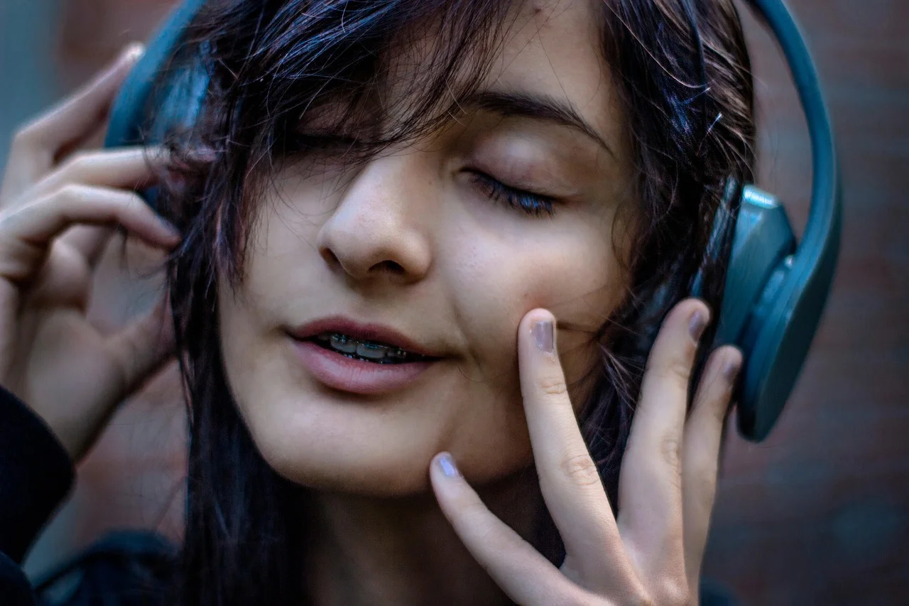 Persona escuchando música con auriculares grandes mientras mantiene los ojos cerrados y una expresión relajada