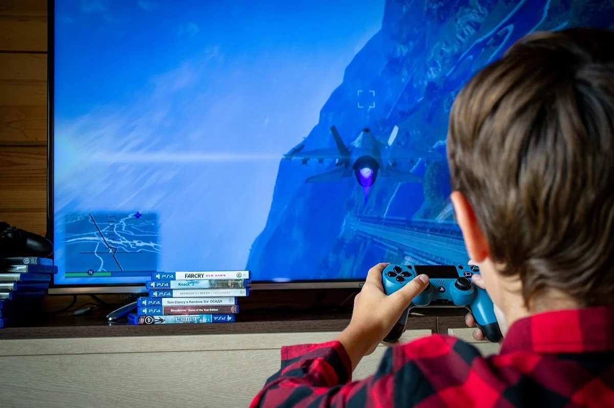 Niño jugando a un videojuego de avión en una consola frente al televisor
